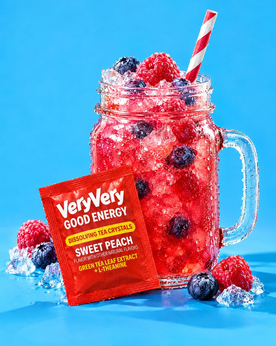 A mason jar of pink berry tea with frozen berries