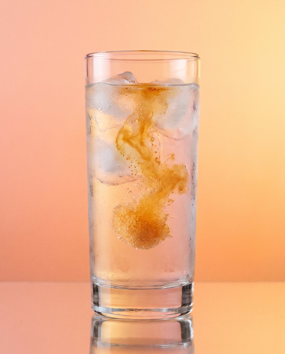 Peach crystals dissolving into a glass of cold water