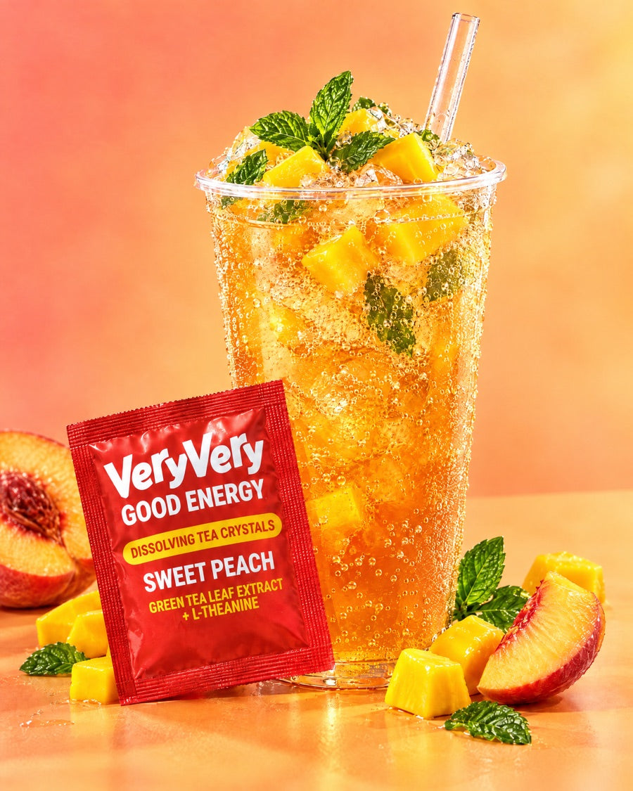 A tall cup of sparkling peach mango iced tea with mint and mango cubes